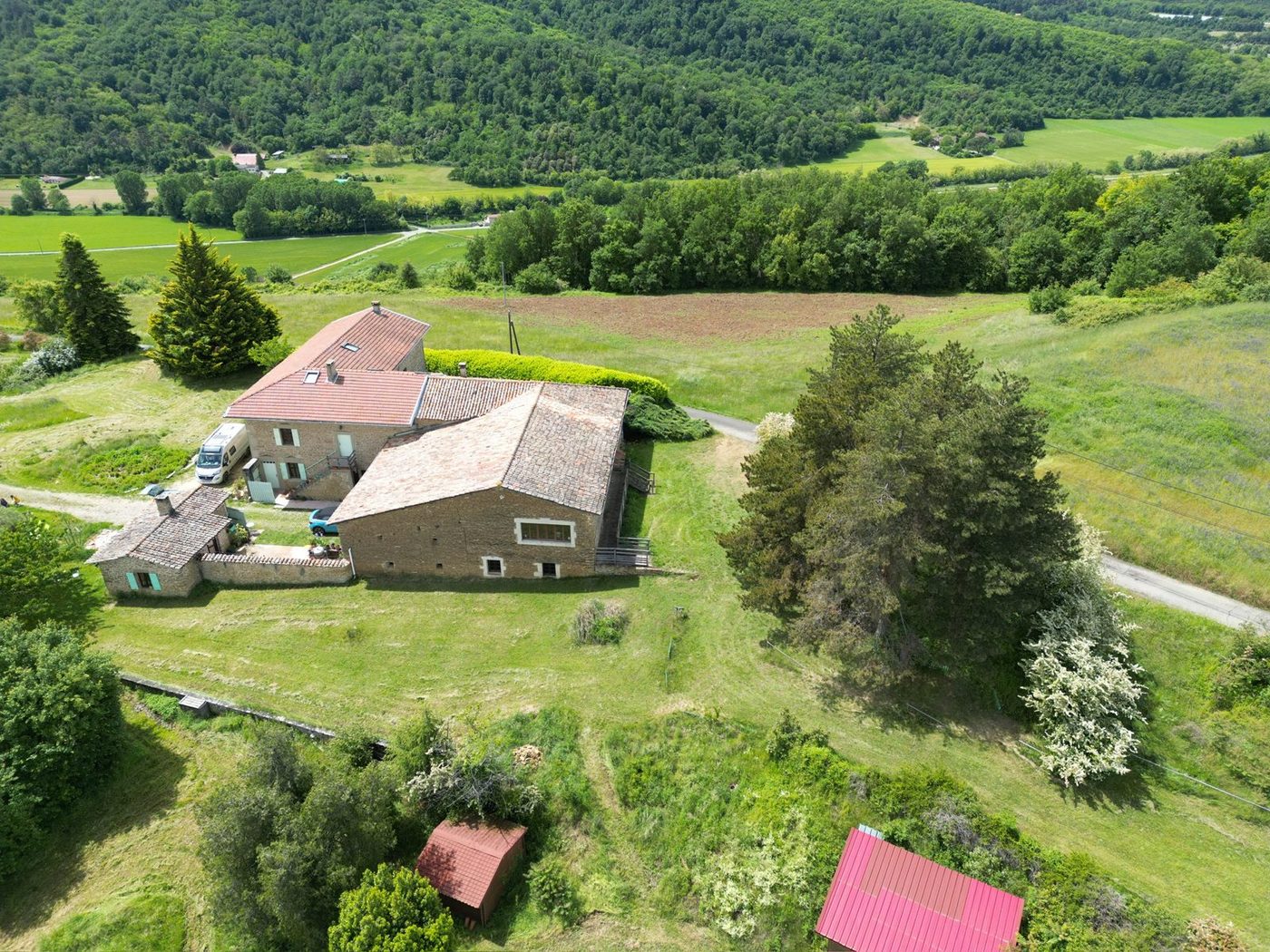 Vue aérienne de la maison et de ses dépendances au milieu des prairies et des bois