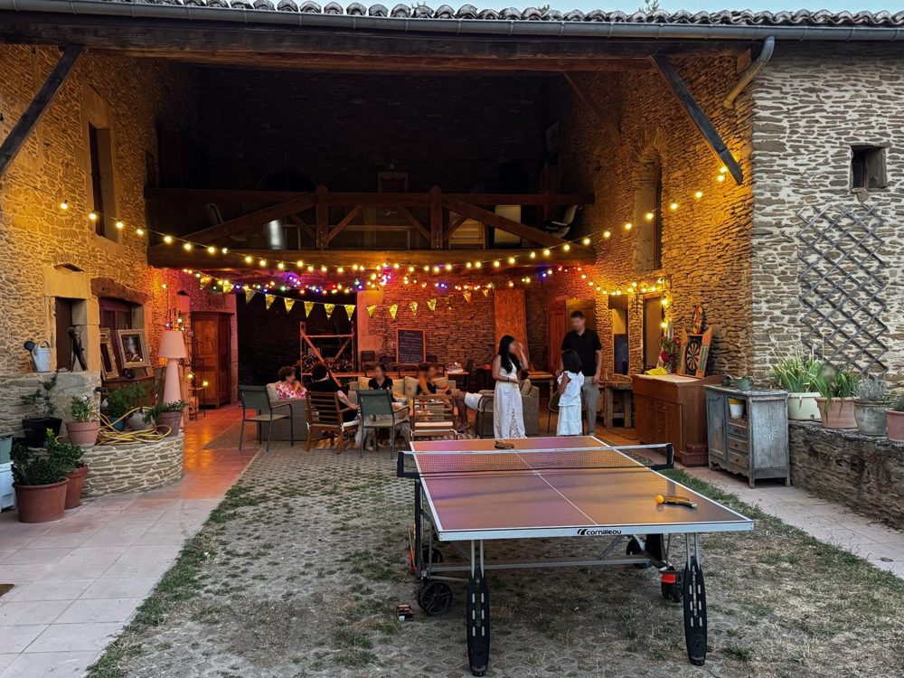 Soirée d'été dans la cour illuminée de guirlandes, table de ping-pong au premier plan