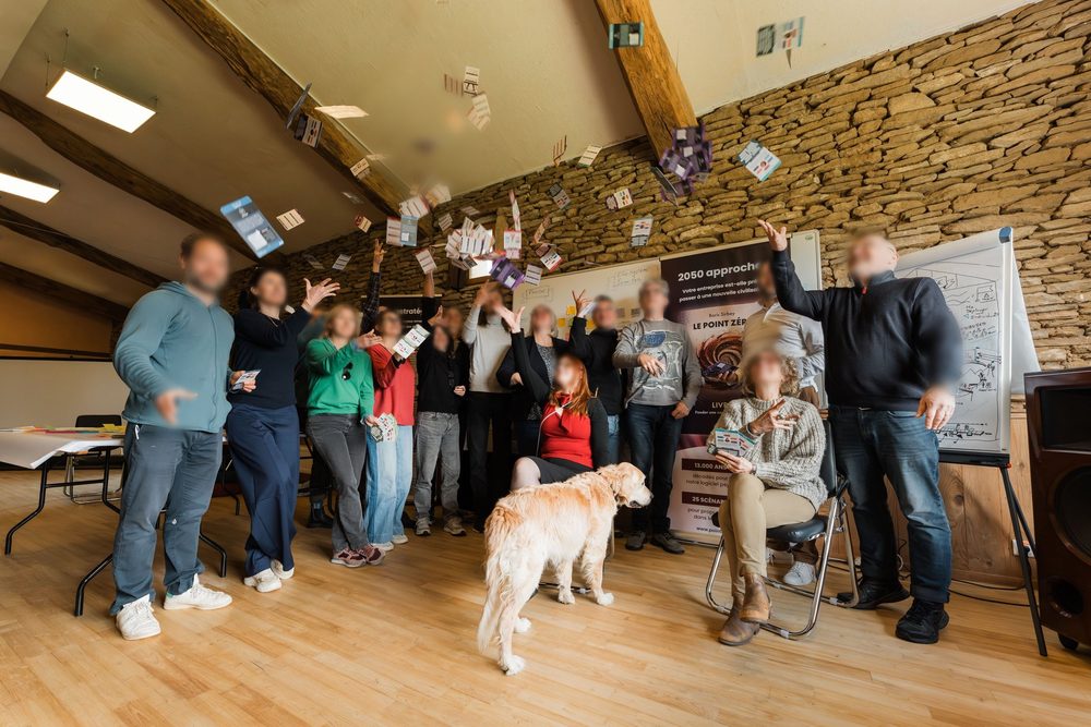 Un groupe lance des papiers en l'air en fin de séminaire, un chien au premier plan