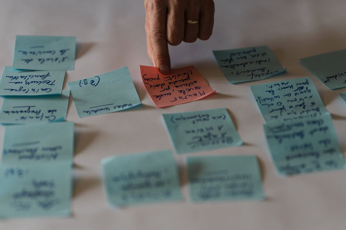 Main désignant un post-it parmi des post-it manuscrits étalés lors d'un atelier