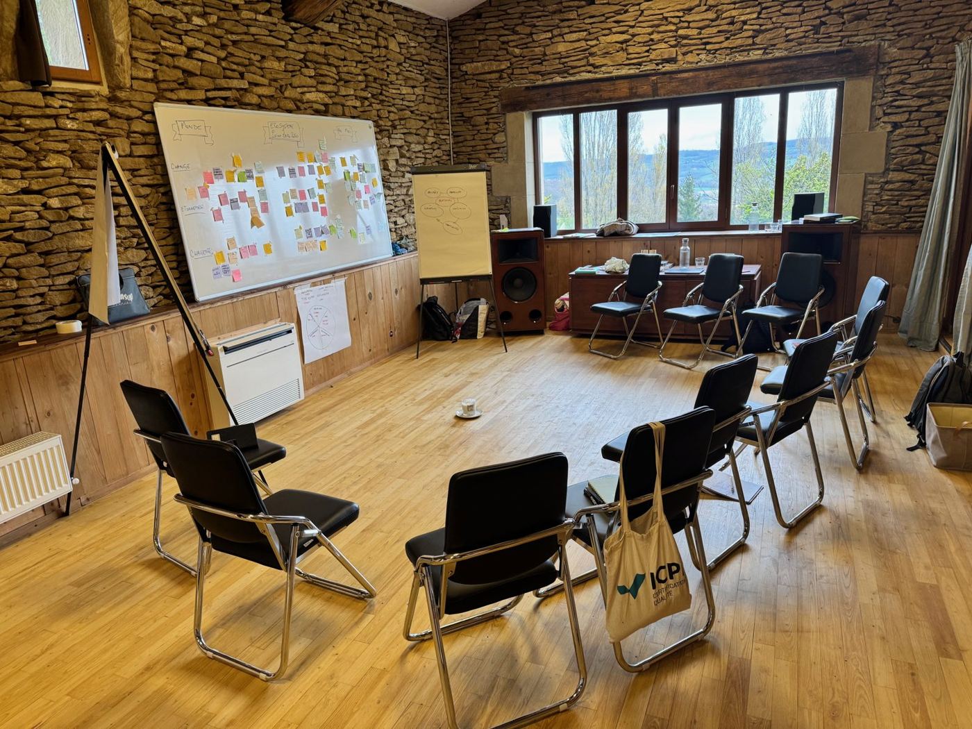 La grande salle en pierre et parquet, chaises disposées en cercle devant un tableau de post-it